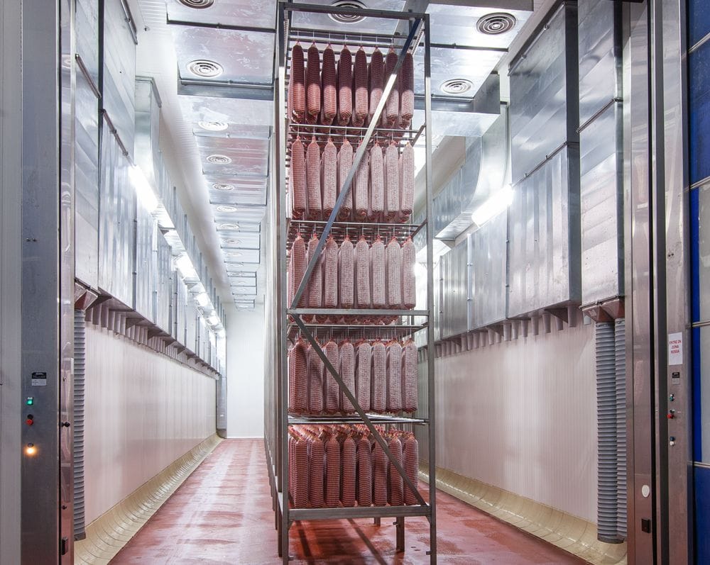 large salami curing room with several racks and many hanging salami